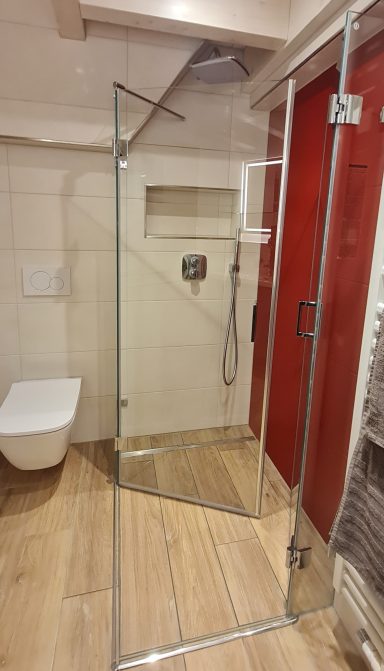Ansicht der Dusche und der Toilette im großen Badezimmer mit Beleuchtung